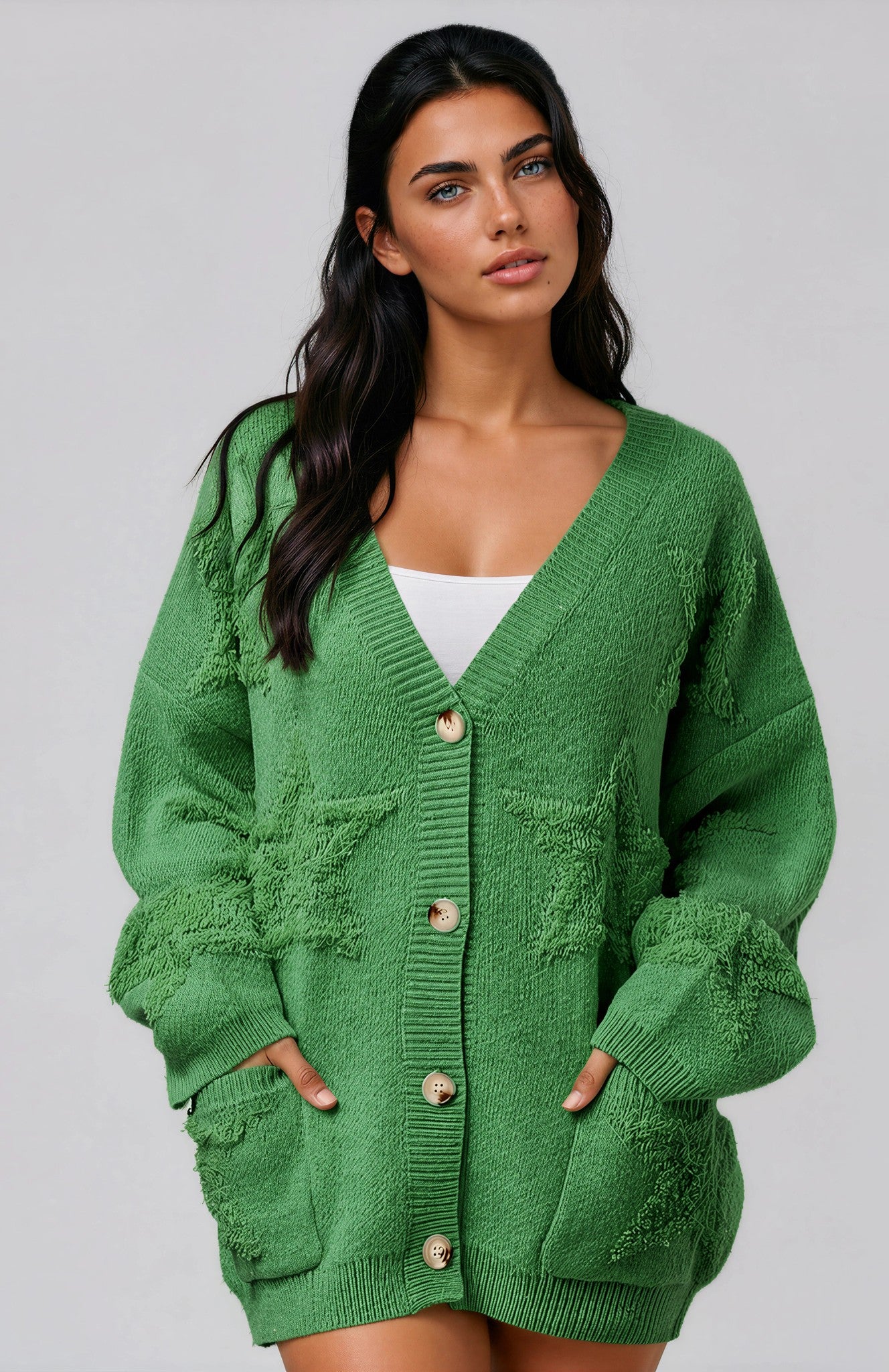 Woman wearing a green cardigan with star print against a grey background