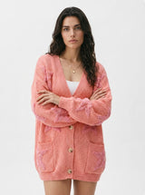 Woman wearing a pink cardigan with star print on a white background