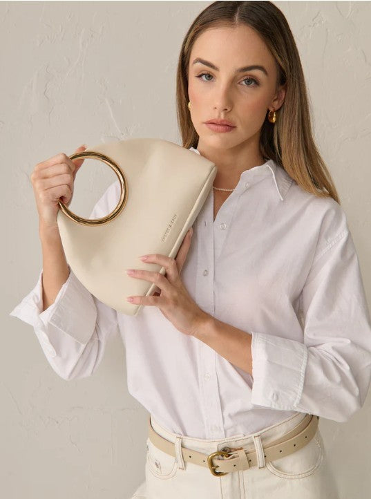Woman holding a beige handbag against a plain background
