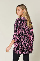 Woman wearing a pink and black zebra print top against a beige background