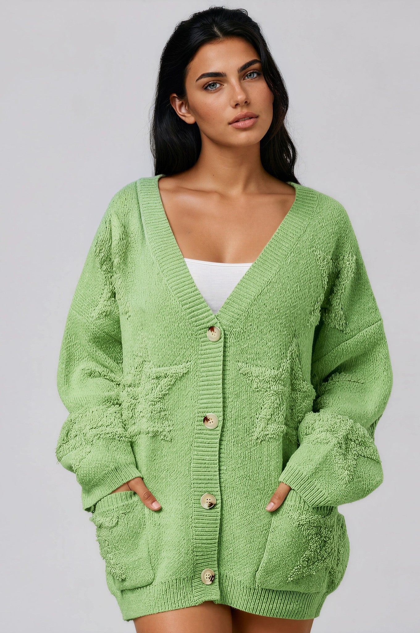 Woman wearing a light green cardigan  with star print against a plain background