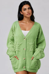 Woman wearing a light green cardigan  with star print against a plain background