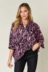 Woman wearing a pink and black zebra print top against a plain background