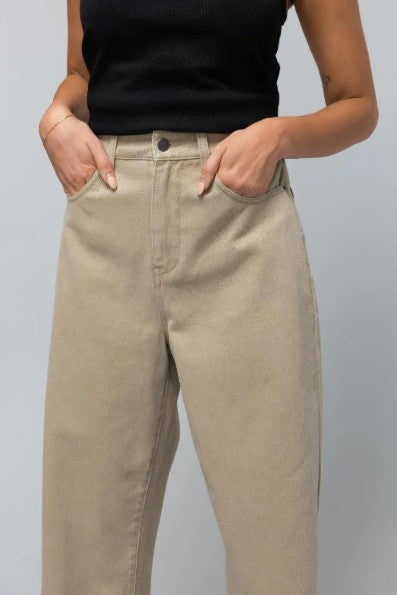 close up of beige coloured denim jeans with the model with her hands in the front pockets on a white background