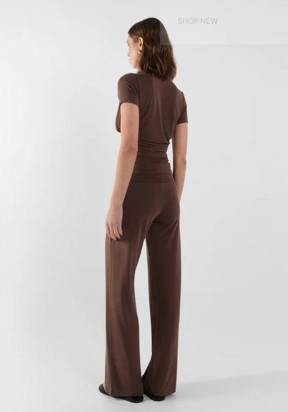 Woman wearing a brown vneck gathered top and pants set on a white background