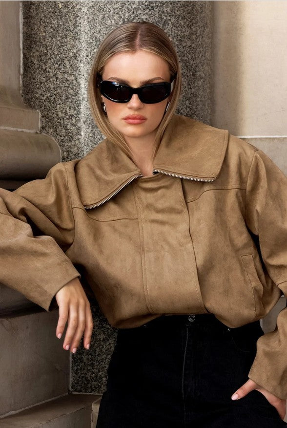Woman wearing a brown jacket and sunglasses in an indoor setting