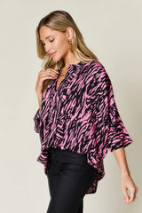 Woman wearing a pink and black patterned blouse against a neutral background