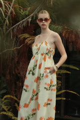 Woman wearing a floral dress in a natural setting with ferns.