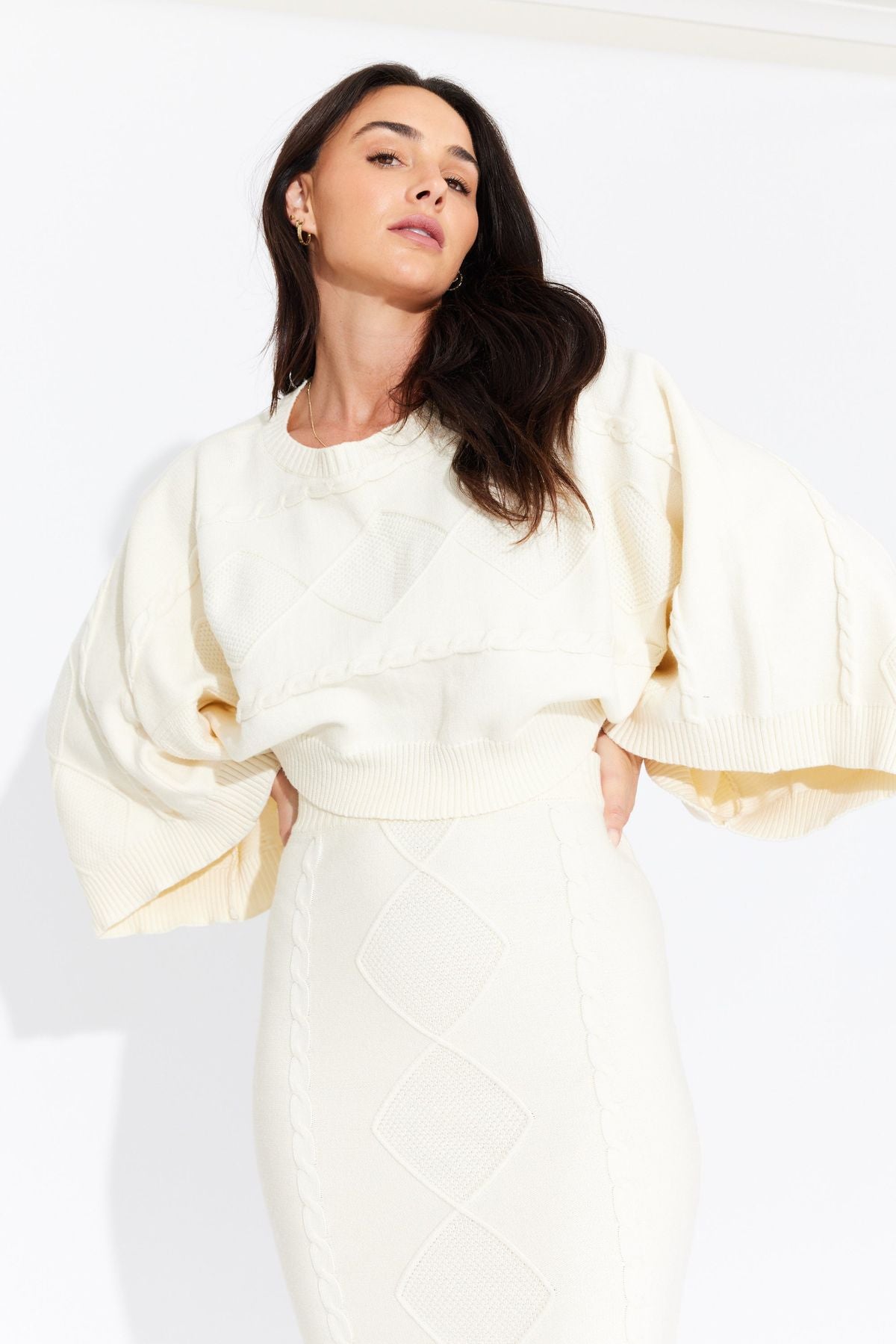 Model wearing the Aggie Knit Top in Butter, captured mid-movement with balloon sleeves in focus. Styled with the Aggie Knit Skirt for a relaxed, head-to-toe winter look.