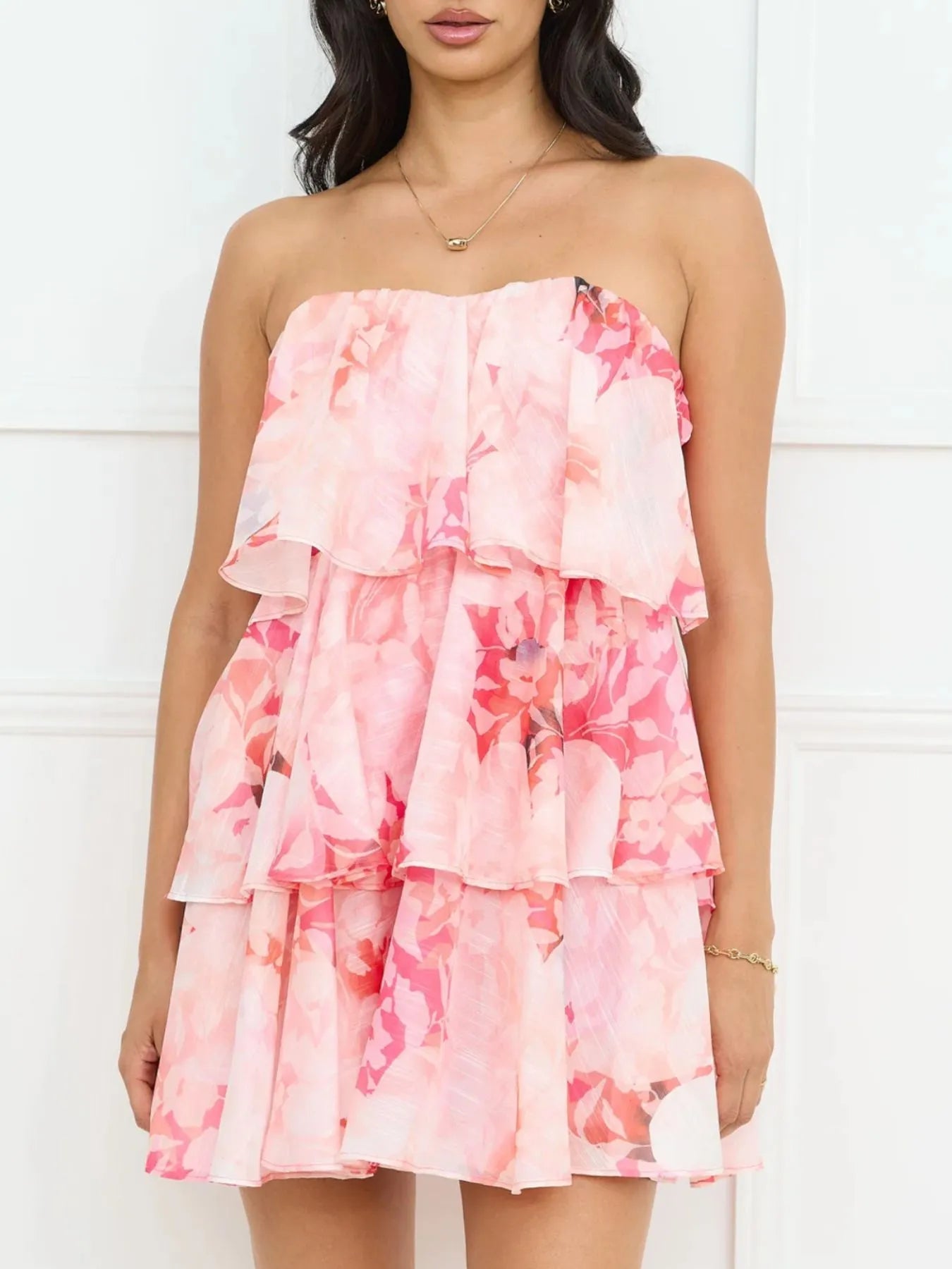 Woman wearing a pink floral strapless dress against a white background