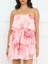 Woman wearing a pink floral strapless dress against a white background