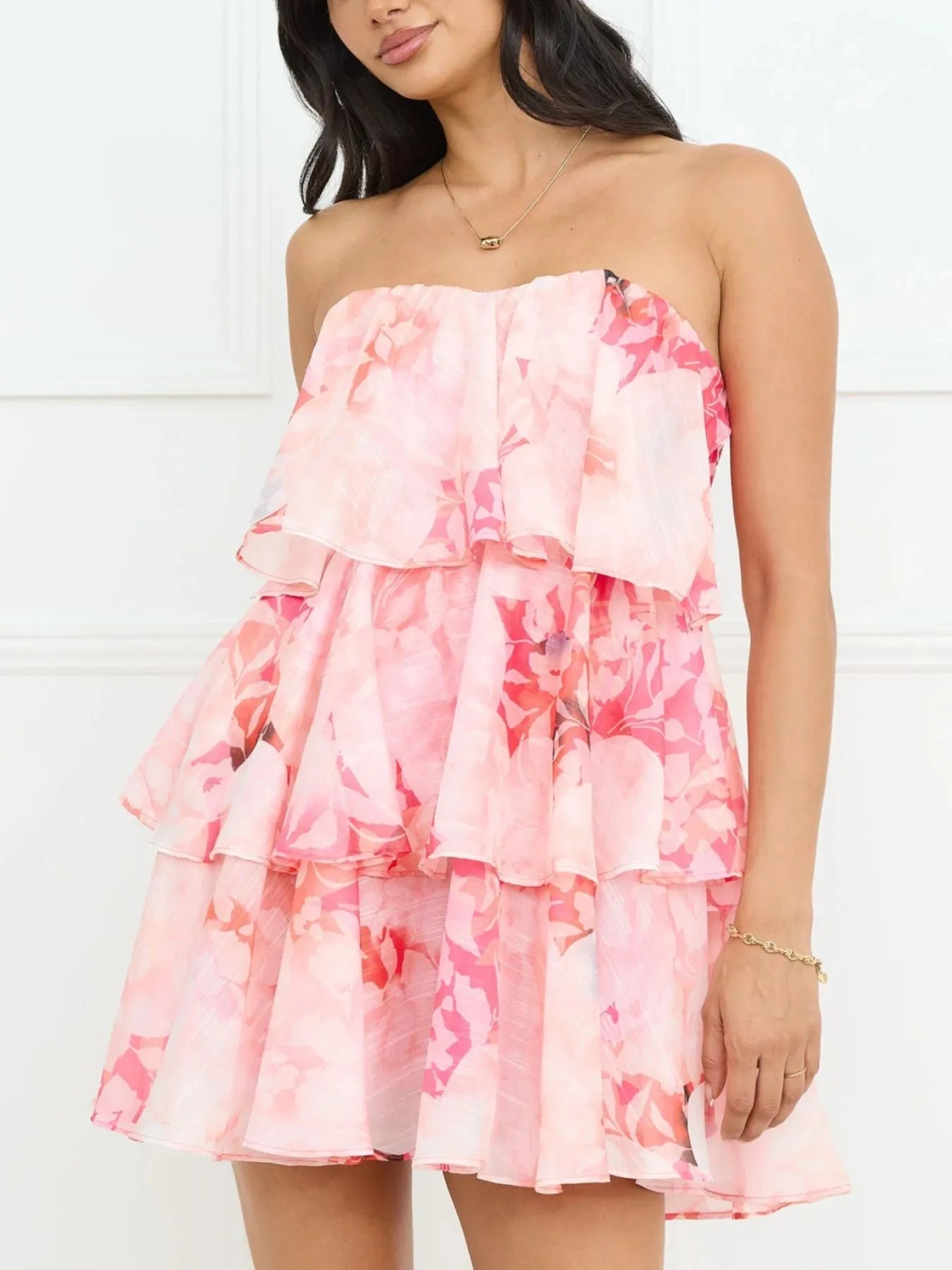 Woman wearing a pink floral strapless dress against a white background