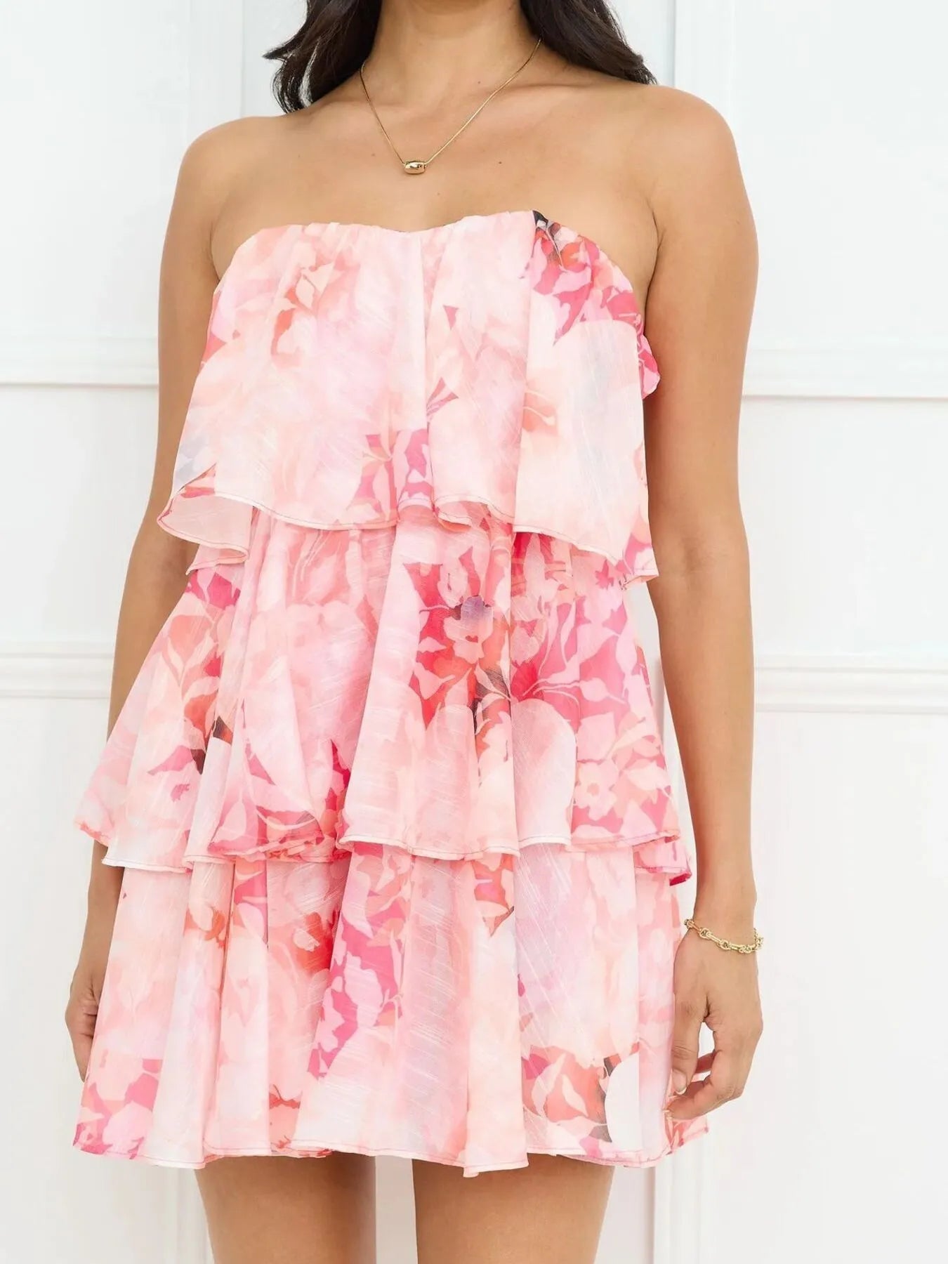 Woman wearing a pink floral strapless dress against a white background
