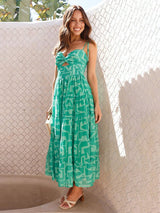 Woman wearing a green patterned dress standing against a textured wall.