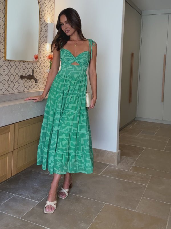 Woman in a green dress standing in a bathroom.