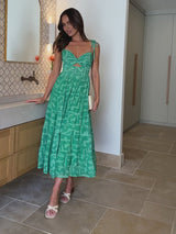 Woman in a green dress standing in a bathroom.