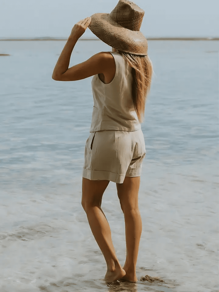 Back view of the Cate Shorts styled with a sleeveless matching vest, walking along the beach.