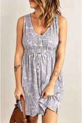 A woman wearing a sleeveless V-neck mini dress with a black and white newspaper print pattern and a button-up front, holding a brown handbag against a light beige background.