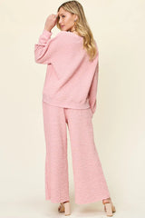 Woman wearing a pink  loungewear pants and top set on a beige background