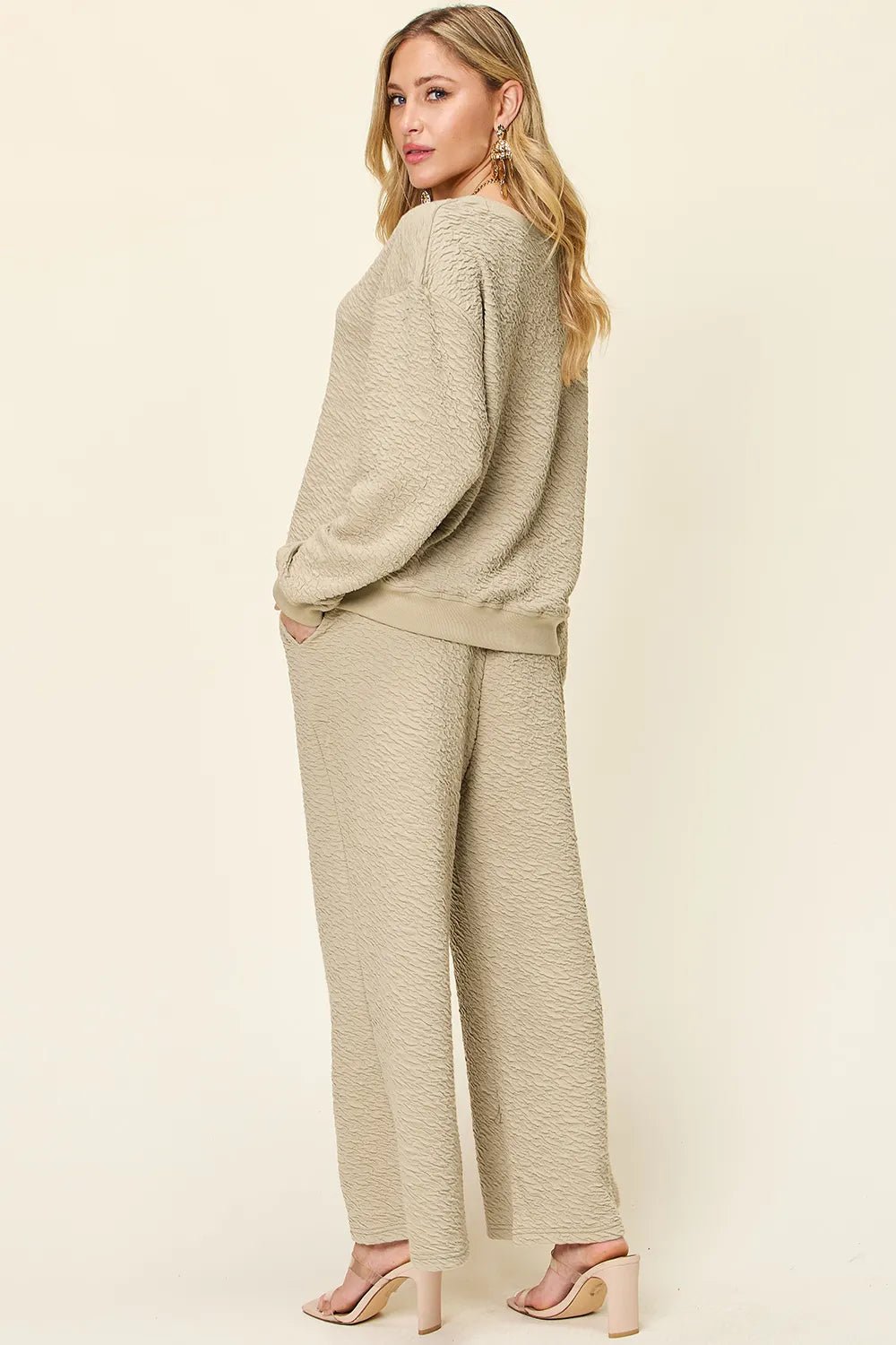 Woman wearing a beige  loungewear pants and top set  on a plain background