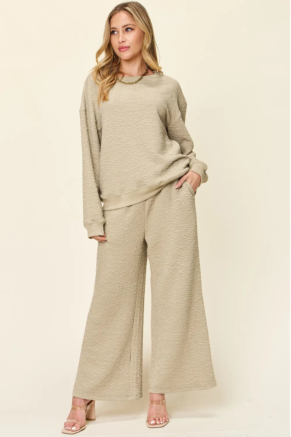 Woman wearing a beige loungewear pants and top set on a plain background