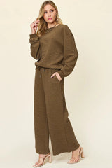 Woman wearing a brown  loungewear pants and top set on a beige background