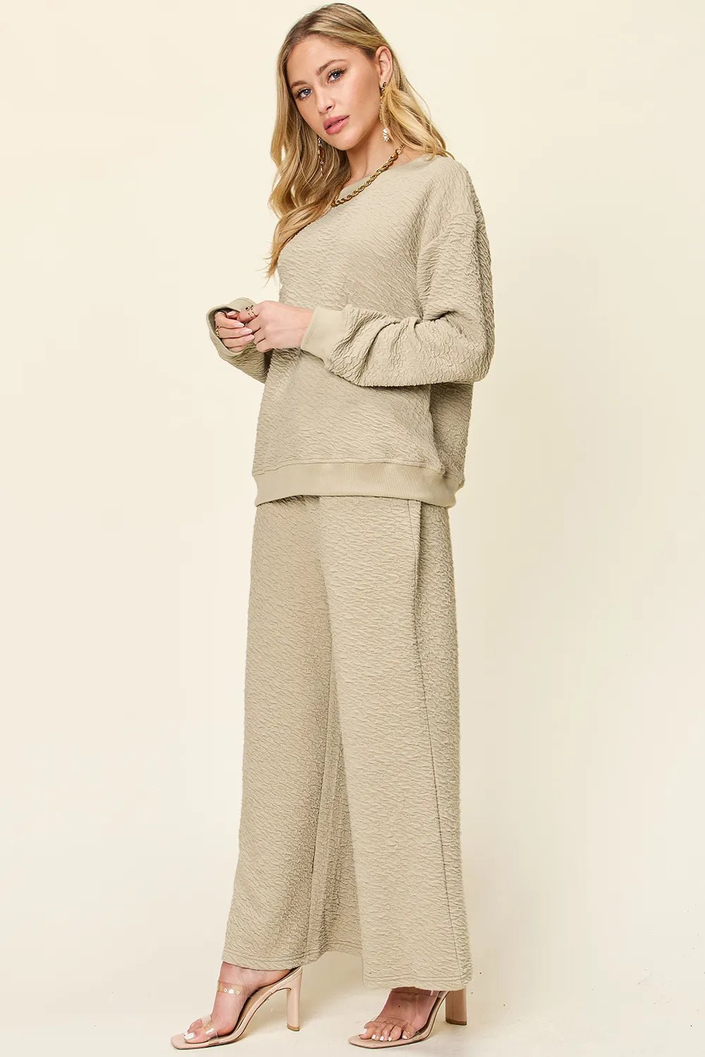 Woman wearing a beige loungewear pants and top set on a plain background