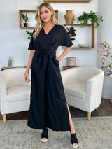 Woman wearing a black jumpsuit in a living room setting