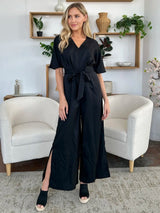 Woman wearing a black jumpsuit in a living room setting