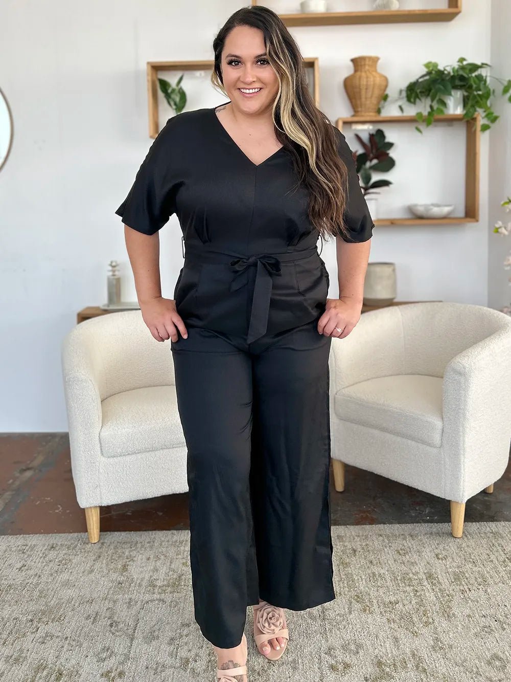 Woman wearing a black jumpsuit in a living room setting