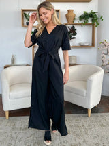 Woman wearing a black jumpsuit in a living room setting
