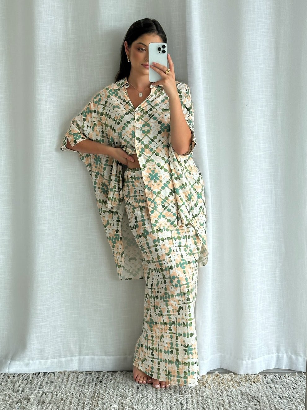 Model takes a mirror selfie in profile view, emphasizing the skirt's flow and the relaxed silhouette of the shirt.