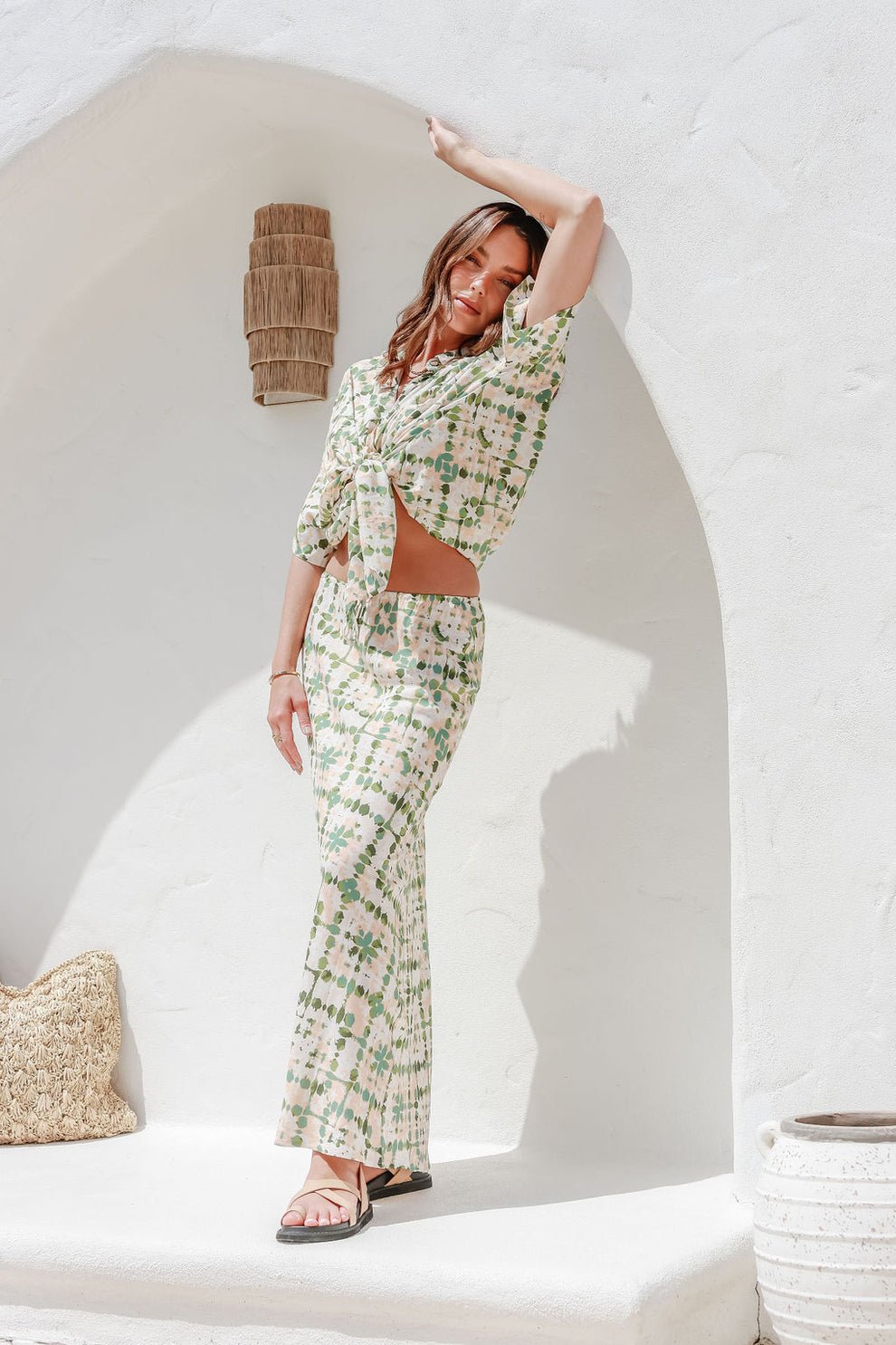 Model poses confidently with arm raised, showcasing the skirt's drape and the shirt's loose fit in natural light.