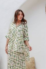 Model styling the Echo Slip Skirt with the matching shirt tied at the waist, leaning casually under a white archway in natural light.