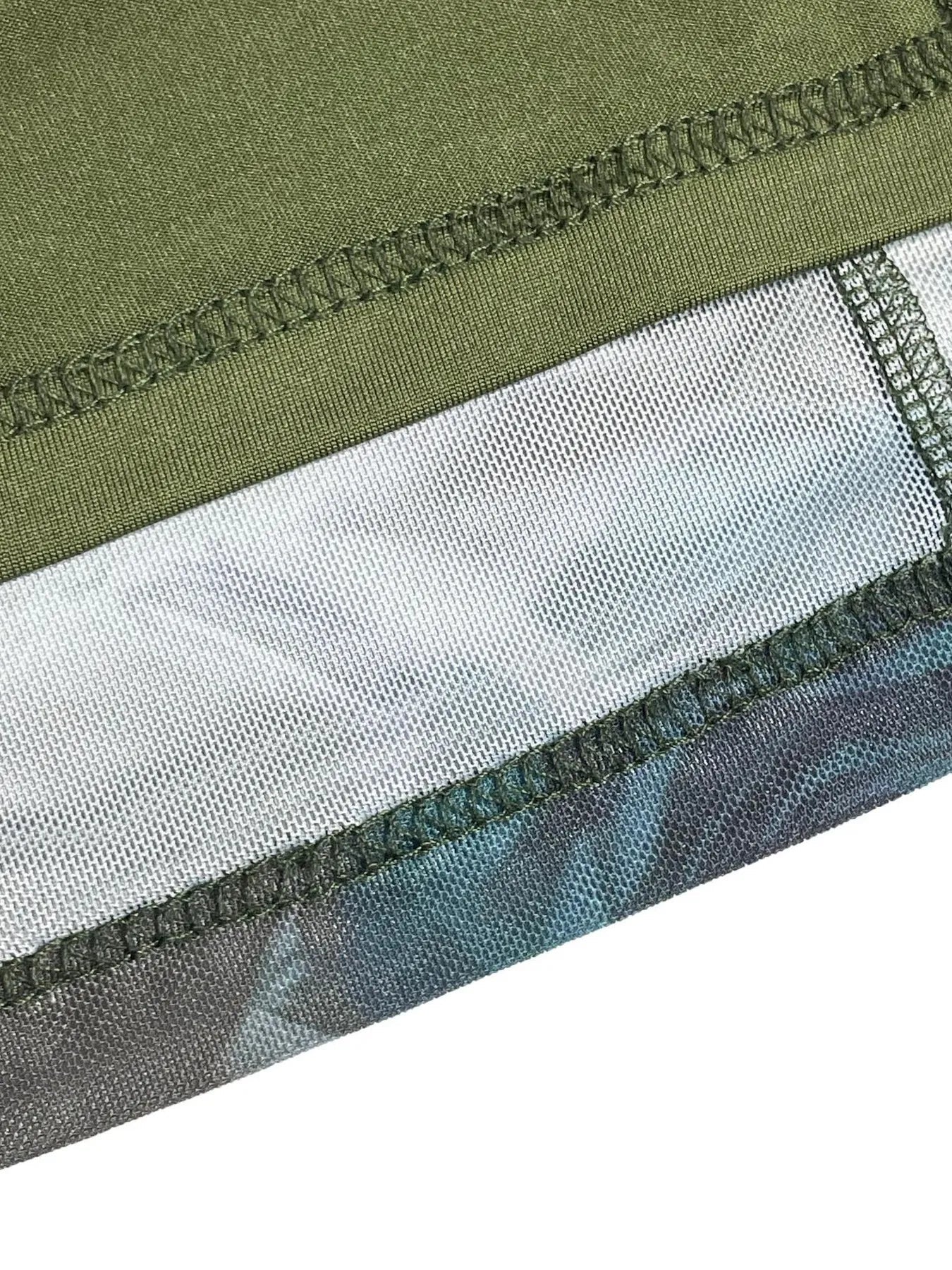 Close-up of a green, gray, and blue fabric with stitching detail on a white background