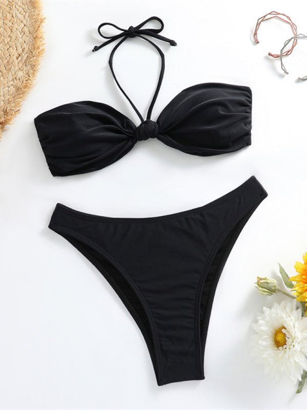 Black bikini set on a white background with flowers and a straw hat.