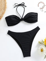Black bikini set on a white background with flowers and a straw hat.