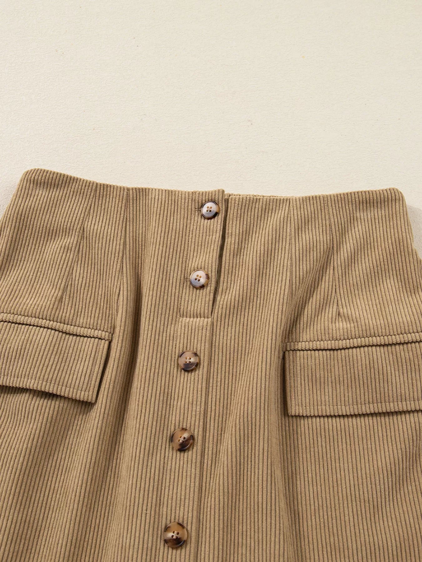 Front button detail of mini skirt hanging on hanger