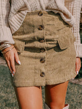 Woman wearing tan corduroy mini skirt with knit sweater and hands in pockets
