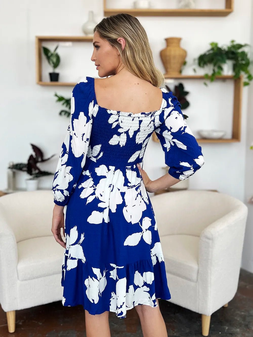 Woman wearing a blue floral dress in a living room setting