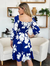 Woman wearing a blue floral dress in a living room setting