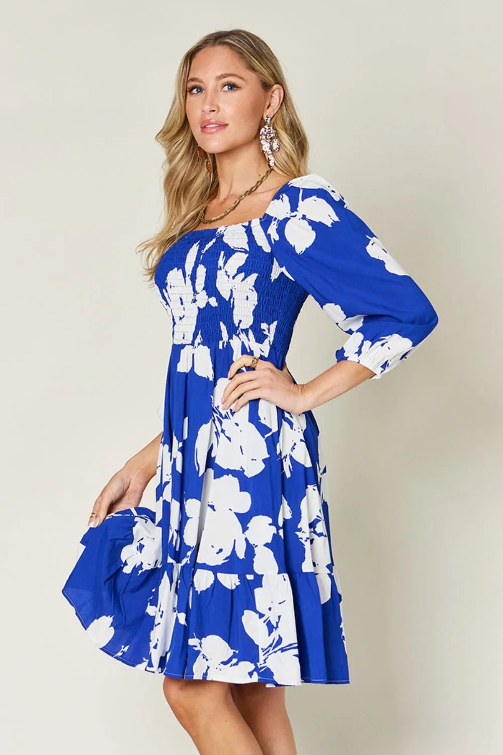 Woman wearing a blue floral dress against a plain background