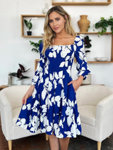 Woman wearing a blue floral dress in a living room setting