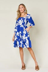 Woman wearing a blue floral dress against a white background