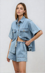 Front view of the light blue denim two piece set styled with a crossbody tan bag.