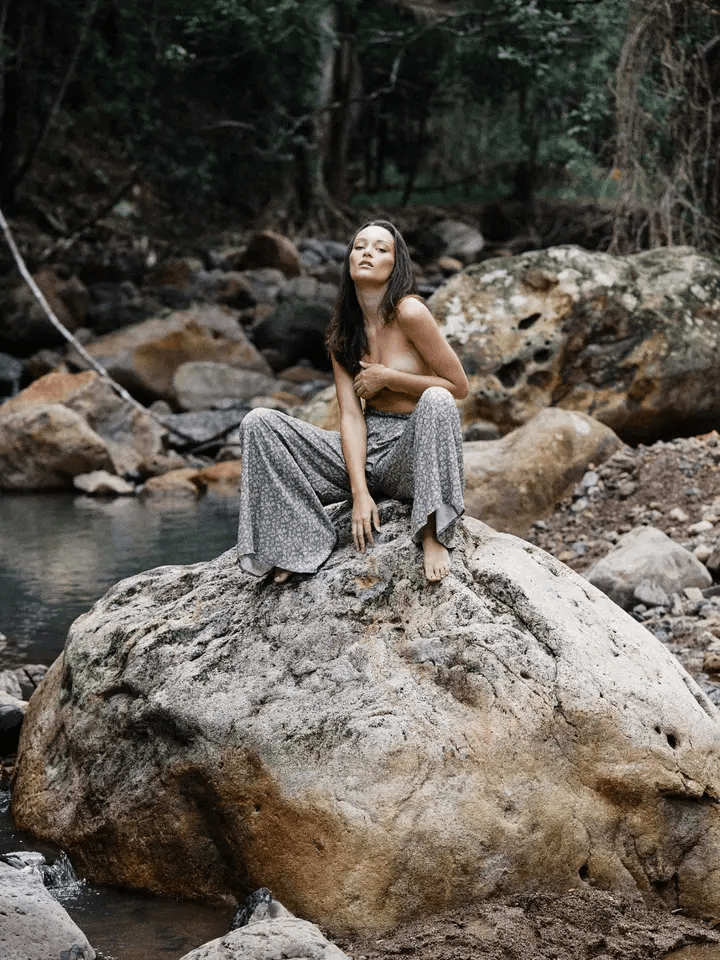 Woman sitting on a rock by a forest stream