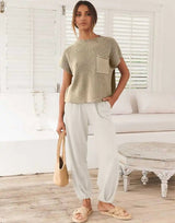 Woman standing in bright room wearing The Marla Pants and Top Set in sage green top and ivory pants.