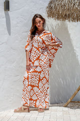Model poses with hands on hips, highlighting the flattering bias cut and bold terracotta print.
