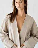 Woman wearing a beige blazer over a white top against a light background