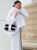 Woman wearing the Rainy Dayz Sweater in white, styled with a grey maxi skirt and black-and-white faux fur handbag.